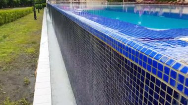 4k video, havuz dokusunun mavi arka planı küçük mavi mozaik fayanslar, açık havuzdan gelen su duvardan aşağı akıyor.