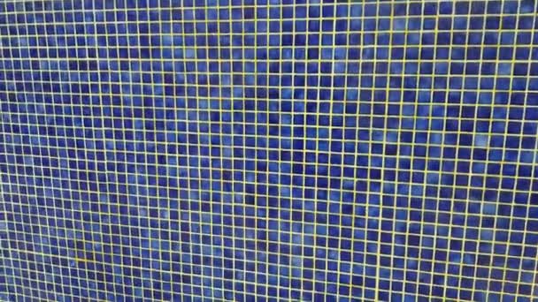 4Kビデオ 小さな青いモザイクタイルとプールのテクスチャの青の背景 屋外プールからの水が壁を流れ落ちる — ストック動画