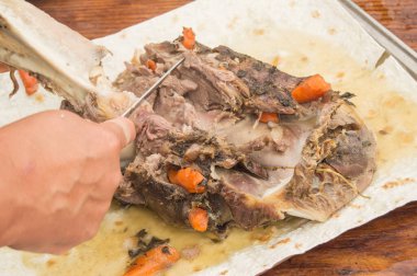 Bir kadının eli, kızarmış eti kemikten ayırır ve bıçakla keser. Aile yemeği için nefis bir et, yakın plan.