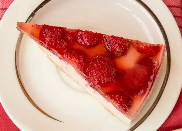 精美的草莓芝士蛋糕放在白盘上 放在桌子上 上面有一张红色的格子餐巾纸 俯瞰全景 — 图库照片
