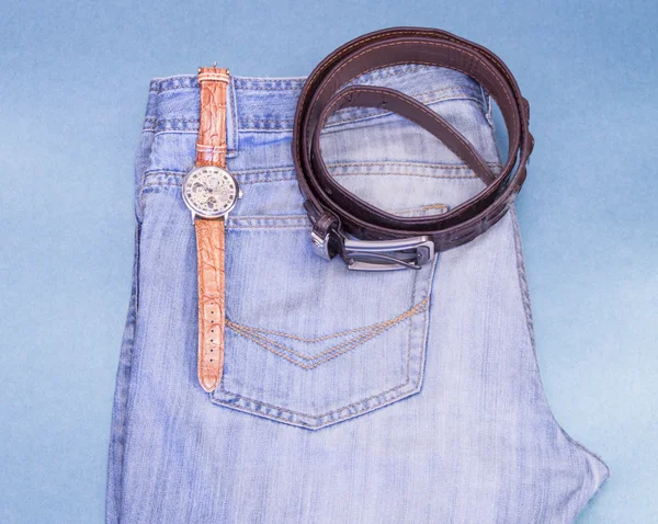 Jeans juveniles, relojes de pulsera, correa de cuero sobre un fondo azul — Foto de Stock