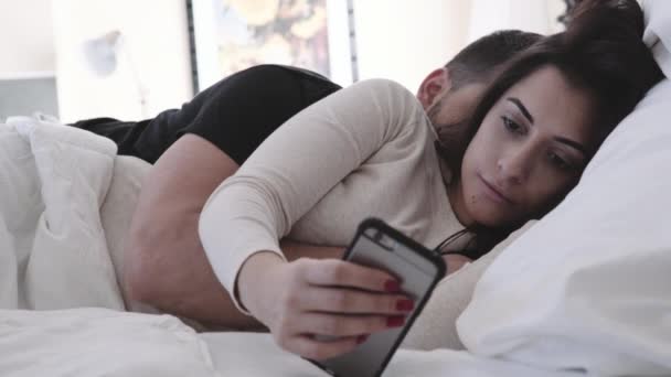 Coppia molto attraente sdraiato a letto guardando il telefono — Video Stock