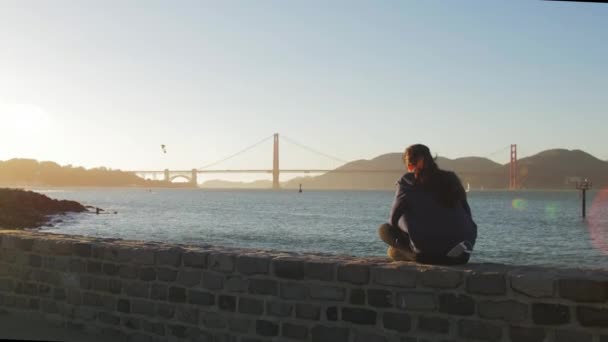 悲伤的年轻女孩坐，看一看金门大桥 — 图库视频影像