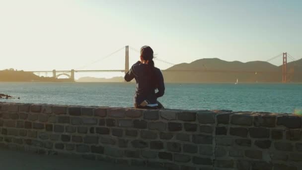 Mädchen Sitzt Und Schaut Auf Die Goldene Torbrücke San Francisco — Stockvideo