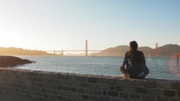 Chica sentada y mirando el puente Golden Gate — Vídeos de Stock