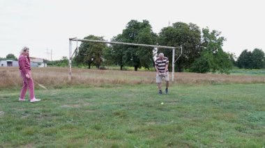 Eski futbol kalelerinin yakınındaki bir sahada badminton oynayan iki kişi, açık havada eğlencenin tadını çıkarıyorlar..