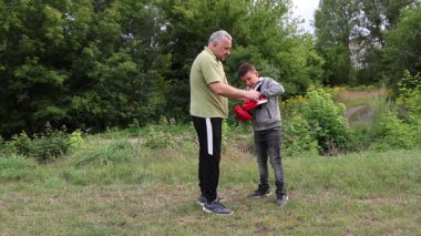 Çocuk, Green Park 'ta yetişkin koçuyla boks antrenmanı yapıyor..