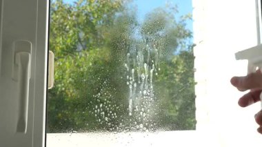 Deterjan pencereye uygulanır. Ev temizliği.