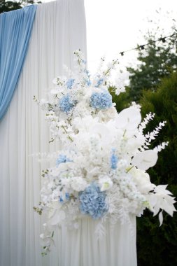 The wedding street arch is decorated with white and blue flowers.                      