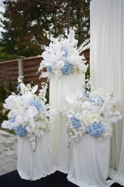 The wedding street arch is decorated with white and blue flowers.            