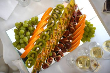 Fruit buffet table: pineapple, kiwi, grapes, orange.          