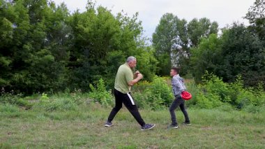 Çocuk, Green Park 'ta yetişkin koçuyla boks antrenmanı yapıyor..