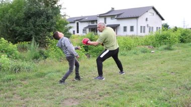 Çocuk, Green Park 'ta yetişkin koçuyla boks antrenmanı yapıyor..