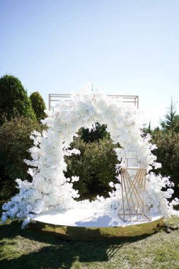 Çalıların yanındaki çimenlikte beyaz çiçeklerin tasarımcısı..