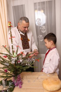 Ukrayna nakış işindeki bir adam ve oğlu Noel ağacı süslemişler..