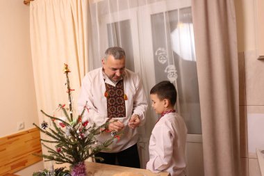 Ukrayna nakış işindeki bir adam ve oğlu Noel ağacı süslemişler..