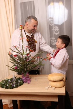 Ukrayna nakış işindeki bir adam ve oğlu Noel ağacı süslemişler..