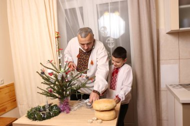 Ukrayna nakış işindeki bir adam ve oğlu Noel ağacı süslemişler..