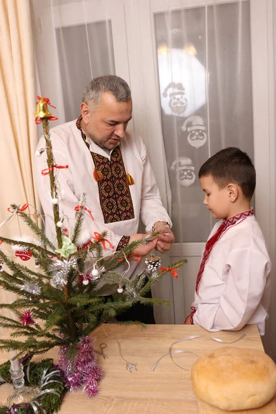 Ukrayna nakış işindeki bir adam ve oğlu Noel ağacı süslemişler..