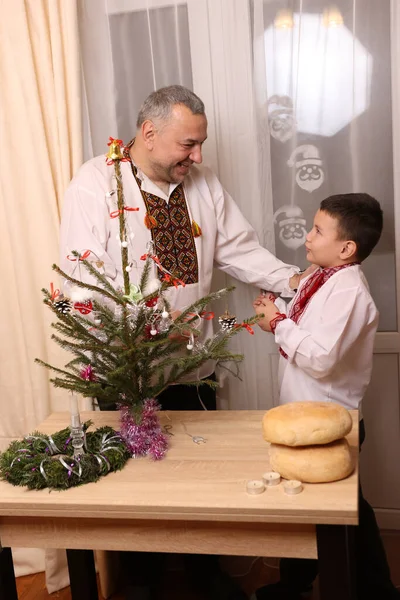 Ukrayna nakış işindeki bir adam ve oğlu Noel ağacı süslemişler..