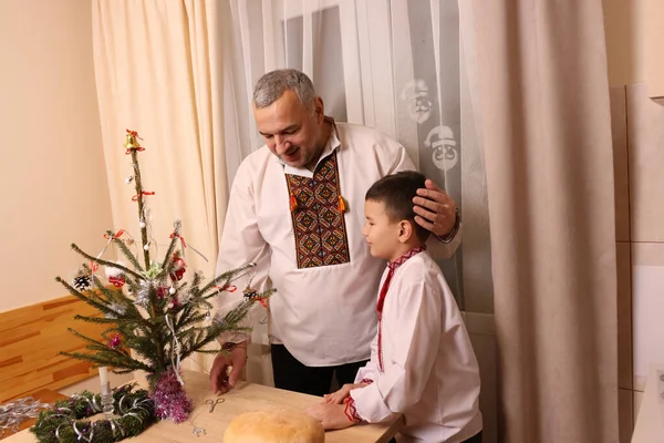 Ukrayna nakış işindeki bir adam ve oğlu Noel ağacı süslemişler..