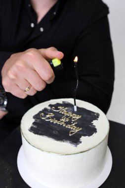 Bir adam doğum günü kutlaması için beyaz bir pastada 