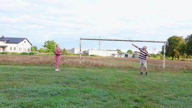 Eski futbol kalelerinin yakınındaki bir sahada badminton oynayan iki kişi, açık havada eğlencenin tadını çıkarıyorlar..