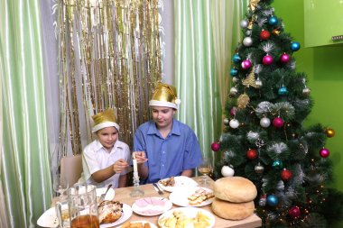 İki çocuk bir masada oturup Noel 'i ya da yeni yılı kutlarken maytap yakıyor..