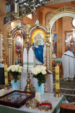 Kilisede düğün töreni, taç, ikon, mum ve sunakta beyaz cüppeli bir papazla..                    