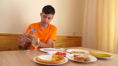 Bir genç masada oturur, su yer ve içer..