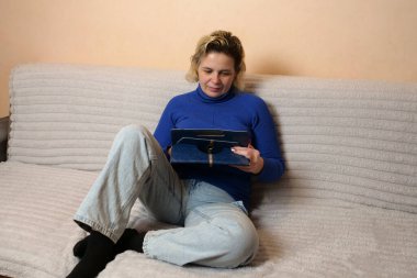 Bir kadın kanepede otururken tablet kullanır..