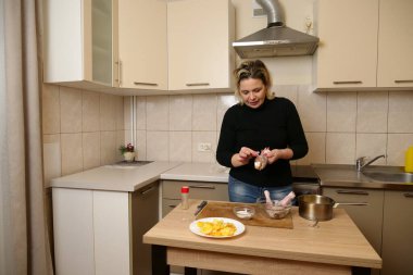 Bir kadın tavuk butlarını kolunda pişirmek için hazırlar..