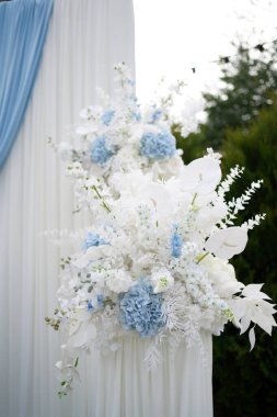 The wedding street arch is decorated with white and blue flowers.                