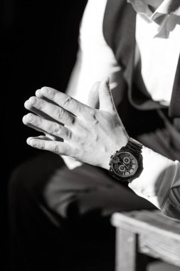 Takım elbiseli bir adamın siyah beyaz fotoğrafı şık bir saate, zarif duruşa ışığın ve gölgenin karşıtlığına odaklan..