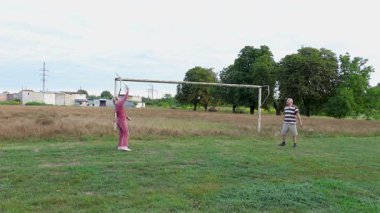 Bir erkek ve bir kadın spor sahasında badminton oynuyorlar, açık havada eğleniyorlar..
