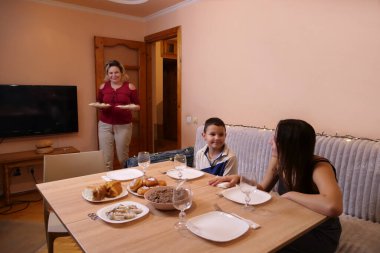 Aile sofrasında sofraya oturur. Bir sürü şenlik yemeği ve Uzvar içkisi..