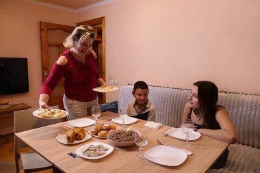 Aile sofrasında sofraya oturur. Bir sürü şenlik yemeği ve Uzvar içkisi..
