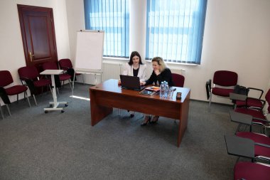 İş sunumunda kadınlar, strateji tartışması yaparken tablolarda listelere işaret ediyorlar.