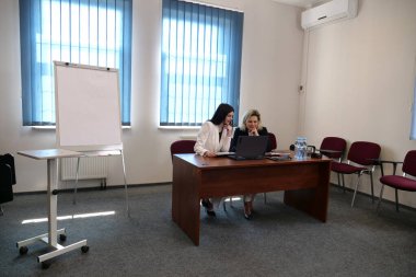 İş sunumunda kadınlar, strateji tartışması yaparken tablolarda listelere işaret ediyorlar.