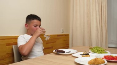 Bir çocuk masada oturuyor ve tatlı olarak dondurma yiyor..