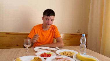 Bir genç masada oturur, su yer ve içer..
