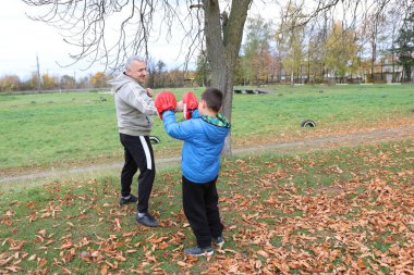 Bir adam ve bir çocuk antrenman eldivenleri üzerinde antrenman yapıyor ve pratik yapıyorlar.