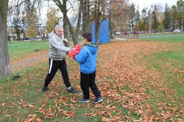 Bir adam ve bir çocuk antrenman eldivenleri üzerinde antrenman yapıyor ve pratik yapıyorlar.