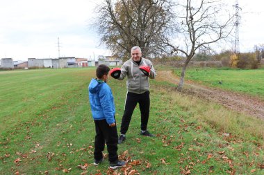 Bir adam ve bir çocuk antrenman eldivenleri üzerinde antrenman yapıyor ve pratik yapıyorlar.
