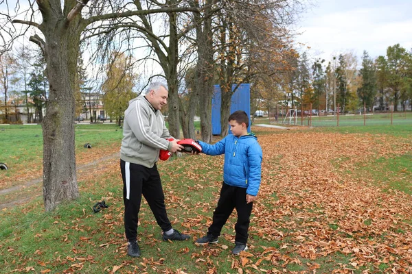 Bir adam ve bir çocuk antrenman eldivenleri üzerinde antrenman yapıyor ve pratik yapıyorlar.