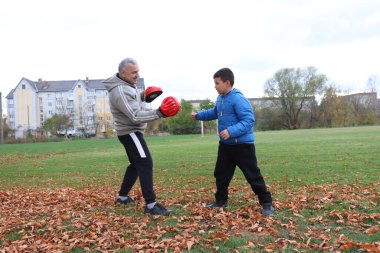 Bir adam ve bir çocuk antrenman eldivenleri üzerinde antrenman yapıyor ve pratik yapıyorlar.