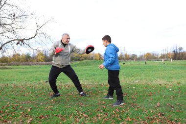 Bir adam ve bir çocuk antrenman eldivenleri üzerinde antrenman yapıyor ve pratik yapıyorlar.