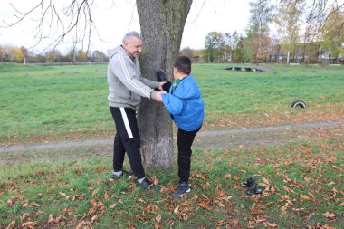Bir adam ve bir çocuk antrenman eldivenleri üzerinde antrenman yapıyor ve pratik yapıyorlar.