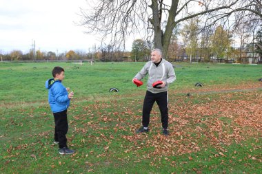 Bir adam ve bir çocuk antrenman eldivenleri üzerinde antrenman yapıyor ve pratik yapıyorlar.