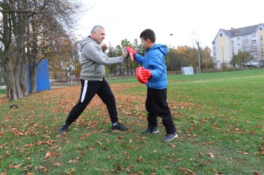 Bir adam ve bir çocuk antrenman eldivenleri üzerinde antrenman yapıyor ve pratik yapıyorlar.